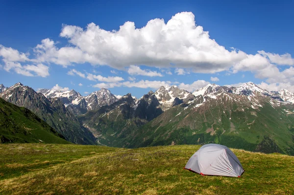 Grijze tent in gras op achtergrond van bergen en rotsen — Stockfoto