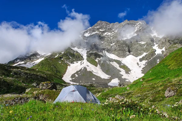 Gray tent in grass on background of mountains and rocks — Stock Photo, Image
