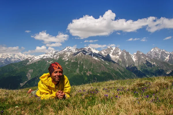 Mann liegend auf Gras Hintergrund von schneebedeckten Gipfeln die Berge Georgien — Stockfoto
