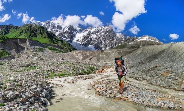 Der Tourist mit einem großen Rucksack überquert die Furt des Flusses. — Stockfoto