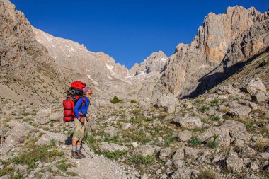 Büyük sırt çantalı bir adam vadide duruyor ve Aladaglar dağlarına bakıyor. Türkiye