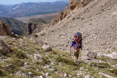 Baba ve kızı, bir sırt çantası taşıyarak Aladaglar dağlarındaki geçitten iniyorlar. Türkiye