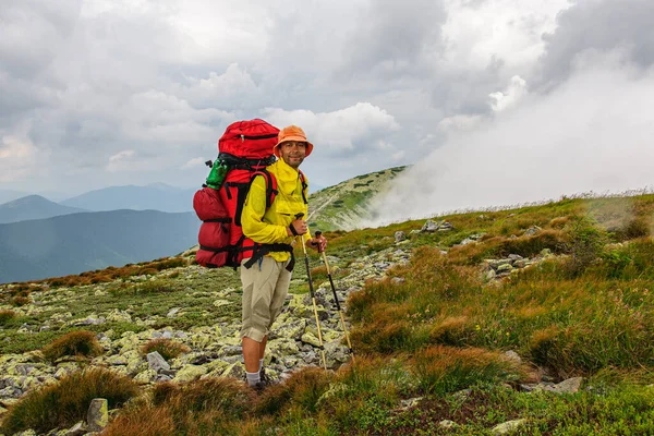 Ein Männlicher Tourist Mit Einem Großen Rucksack Erklimmt Einen Bergsteinpfad Stockfoto