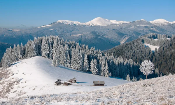 Winter landschap met een bergdal. Een houten kruis met een kruisbeeld in de buurt van de hut. — Stockfoto