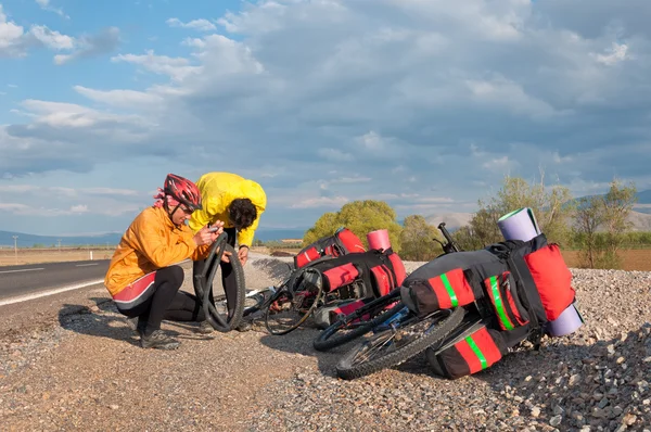 Dos hombres reparando su bicicleta rota — Foto de Stock