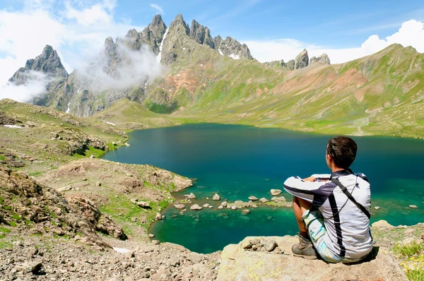 L'uomo ammira un bellissimo lago in montagna — Foto Stock