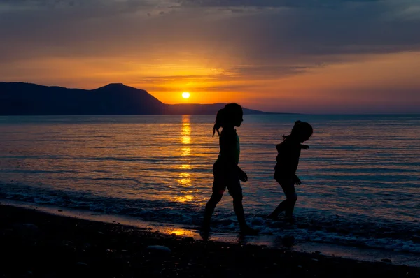 Two girls walking along the beach during sunset — Stock Photo, Image