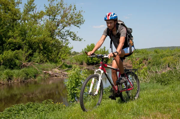 Ciclista de montaña junto a un hermoso río — Foto de Stock