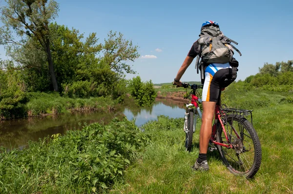 Ciclista de montaña junto a un hermoso río — Foto de Stock