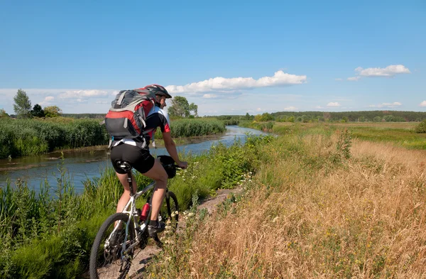 Ciclista de montaña junto a un hermoso río — Foto de Stock