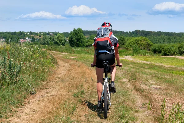 Ciclista montando una bicicleta de montaña en dirección al pueblo — Foto de Stock