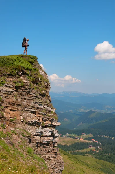 Человек с рюкзаком стоит на скале — стоковое фото