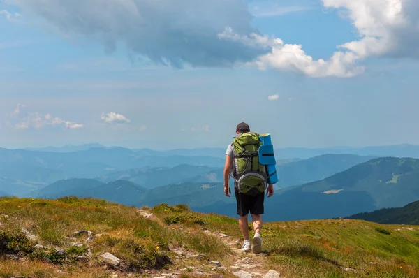 Tourist stands on hill and looks mountain — Stock Photo, Image