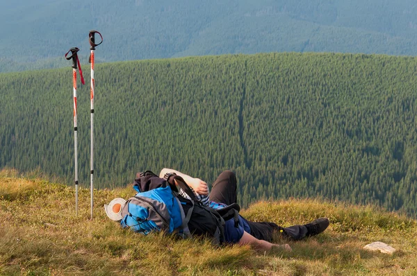 Tired hiker relaxes on a slope in the mountains — Stock Photo, Image