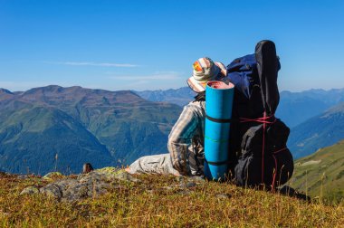 Dağlarda bir yamaçta yorgun hiker rahatlatır