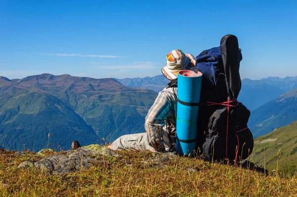 Caminante cansado se relaja en una pendiente en las montañas — Foto de Stock