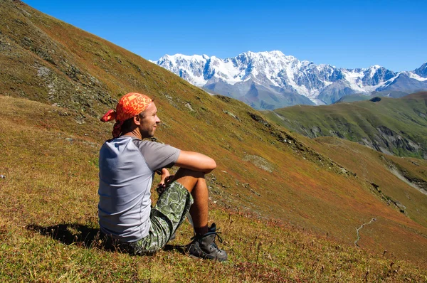 Joven turista descansando en la cima con vistas al valle — Foto de Stock