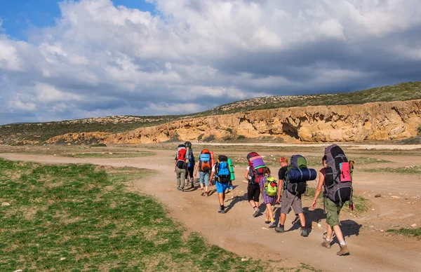 Group of tourists with large backpacks are on road sea — Stock Photo, Image