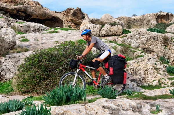 Hombre va playa de arena en bicicleta de montaña con gran mochila . — Foto de Stock