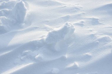 Temiz, beyaz arka plan dokusu. Kar taneleri ve kar yığınlarıyla kışın arka planda. Kar yığınları. Mevsimlik manzara ayrıntıları.