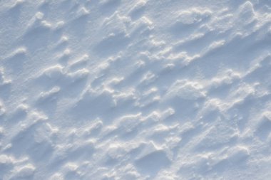 Temiz, beyaz arka plan dokusu. Kar taneleri ve kar yığınlarıyla kışın arka planda. Kar yığınları. Mevsimlik manzara ayrıntıları.