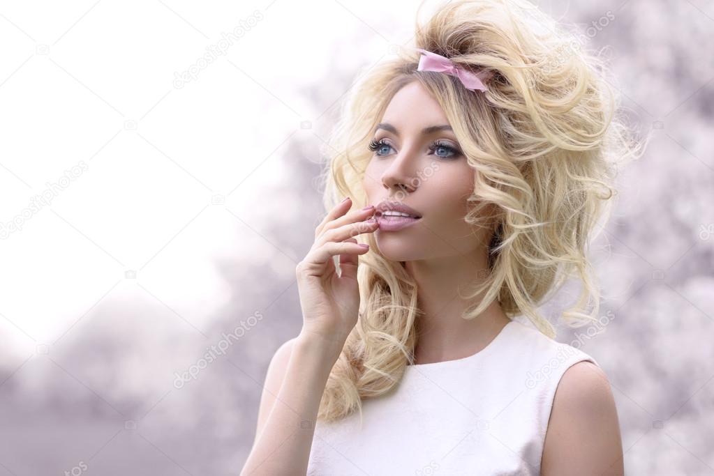 Beautiful blonde girl in flowering cherry garden