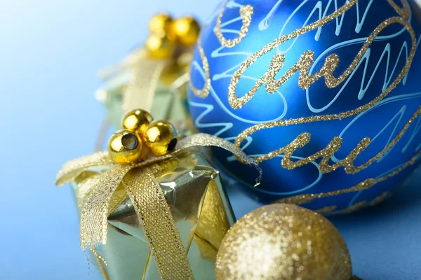 Bola de Natal azul e ouro com caixa de presente presente no fundo azul ano novo — Fotografia de Stock