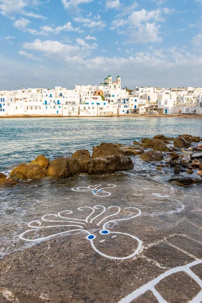 Traditional Cycladitic view with  octopus drawings on the road and  whitewashed houses with the christian church of kimisis Theotokou as a background  in Naousa  Paros island, Greece