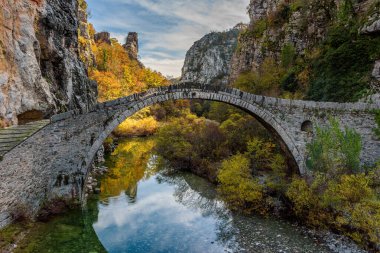 Kokori 'nin sonbahar mevsiminde Zagori, Epirus Yunanistan' daki Voidomatis nehrinde yer alan eski kemer taşı köprüsü (Noutsos).