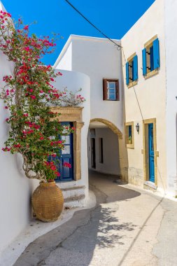 Yunanistan 'ın Chora Kythira adasında dar sokaklar, beyazlatılmış evler ve çiçek açan bir bougainvillea ile geleneksel ara sokak.