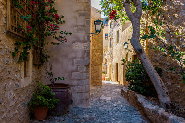Traditional architecture with narrow stone street and a colorfull bougainvillea in the medieval castle of Monemvasia, Lakonia, Peloponnese, Greece.