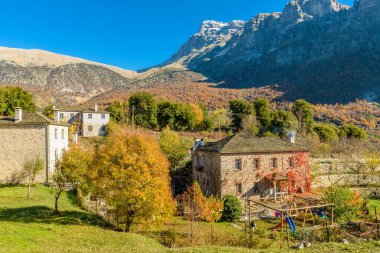 Yunanistan 'ın Zagori kentindeki Papigo köyünde sonbahar mevsiminde, arka plan olarak taş binalar ve astraka dağına sahip geleneksel mimari