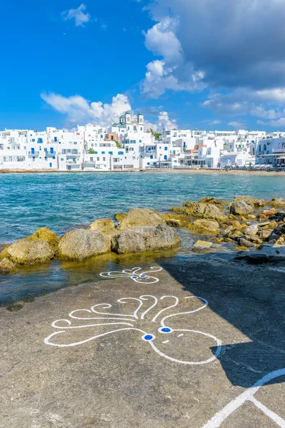 Traditional Cycladitic view with  octopus drawings on the road and  whitewashed houses with the christian church of kimisis Theotokou as a background  in Naousa  Paros island, Greece