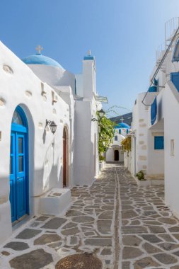 Yunanistan 'ın Parikia, Paros adasında, mavi kubbeli, dar bir caddesi ve iki beyazlatılmış kilisesi olan geleneksel Cycladitic sokağı.