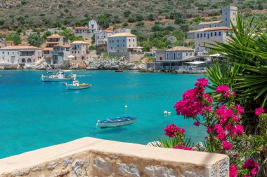 Limeni köyünde ünlü taş binalar çiçek açan bir bougainvillea ve Mani, Güney Moreloponnese, Yunanistan 'da turkuaz sular.
