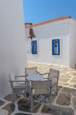 Dar bir sokak beyazlatılmış evleri ve Chora Kythnos, Cyclades, Yunanistan 'da sandalyeli bir masası olan geleneksel Kiklad sokağı..
