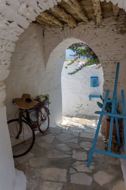 Yunanistan 'ın ano Syros bölgesinde dar bir sokak, beyaz bir kemer ve bir bisikletle geleneksel sikladitik sokak.