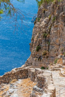 Yunanistan 'ın Kiklad adasındaki Amorgos adasında Ege Denizi üzerindeki bir kayanın üzerindeki ünlü Hozoviotissa Manastırı' na uzanan taştan yol manzarası.