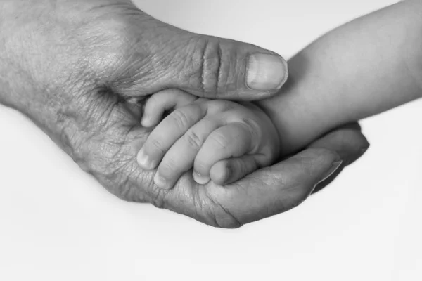 Old man's wrinkled hand holding infant's little hand