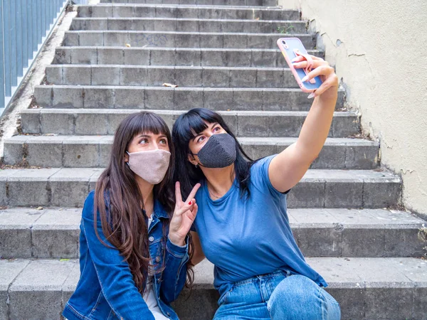 Zwei Junge Kaukasische Frauen Sitzen Draußen Und Machen Ein Selfie lizenzfreie Stockfotos