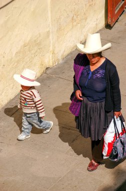 Cajamarca, Peru - Ekim 2019: Bir anne ve bir çocuk geleneksel yerli şapkalarıyla sokaklarda yürüyor. Tipik kıyafetleri olan Perulu bir aile..