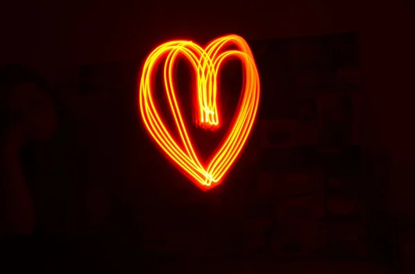 Heart shape made with red light in long exposure with black background. Light painting photography. Valentine\'s day and love concept. Vibrant heart outline.