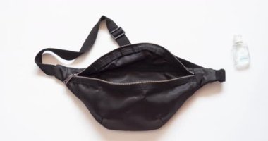 Antibakteriyel ve maske de dahil olmak üzere salgın sırasında sokağa çıkmak için gerekli malzemelerin olduğu siyah bir paket. İçinde para, güneş gözlüğü ve cep telefonu olan bir çanta. Hareket videosunu durdur. 