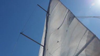 Akdeniz 'de mavi gökyüzü olan yelkenli direği. Tatil, yaz ve macera konsepti. Ana yelken rüzgarda açılır.