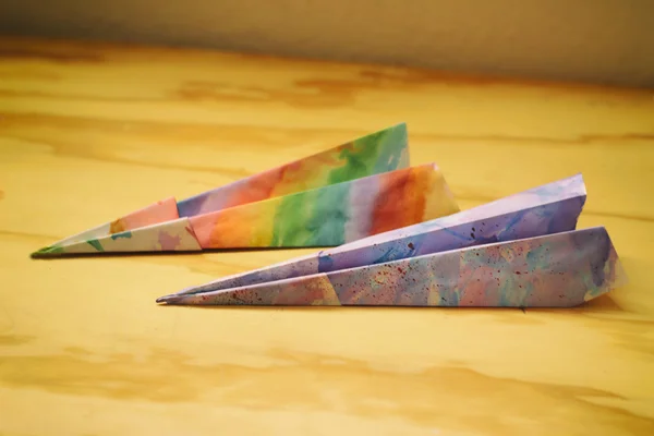 Papír barevný letadla na dřevěný stůl — Stock fotografie