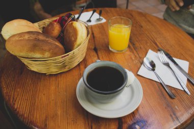 Bir fincan kahve, bir sepet ekmek ve bir bardak portakal suyu.