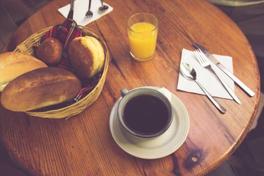 Bir fincan kahve, bir sepet ekmek ve bir bardak portakal suyu.