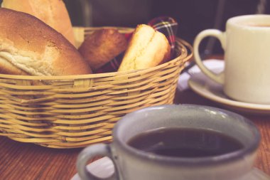 Bir fincan kahve, bir sepet ekmek ve bir bardak portakal suyu.