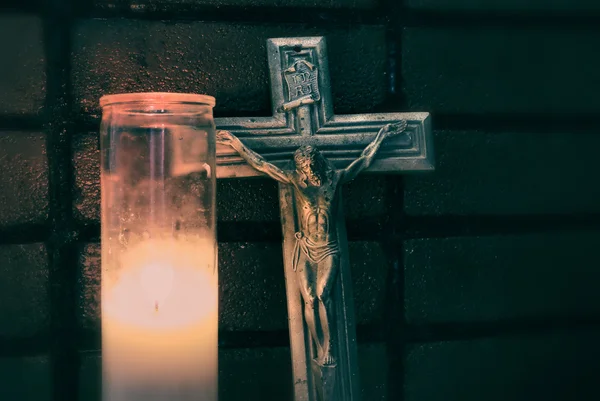 Crucifixo perto de vela de iluminação — Fotografia de Stock