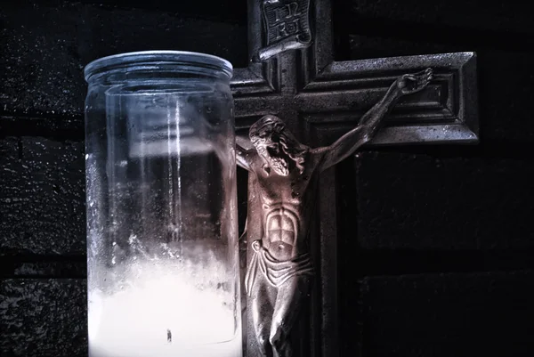 Crucifixo perto de vela de iluminação — Fotografia de Stock